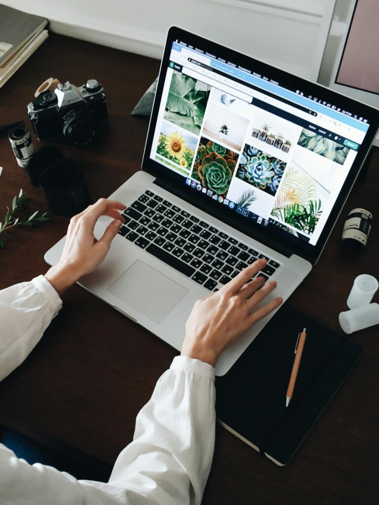 Person working on laptop with film camera nearby. Perfect for technology and lifestyle themes.