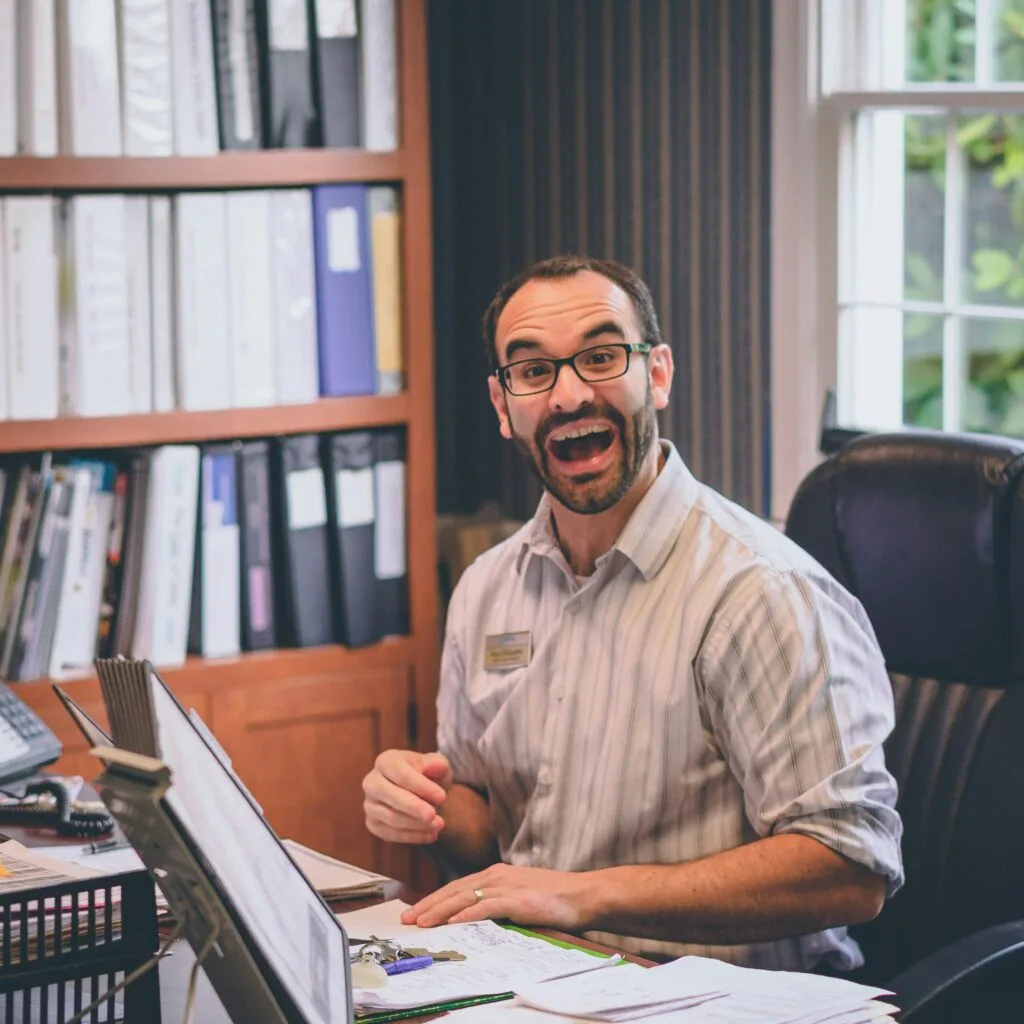 pexels-photo-1546912-1546912 Man with glasses and beard looking excited while working at an office desk.